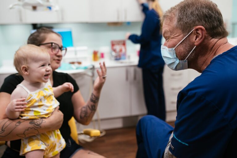 Richmond Pediatric Dentistry & Orthodontics | 5 Locations 3 A smiling baby on a parent's lap during a first dental visit at RPDO